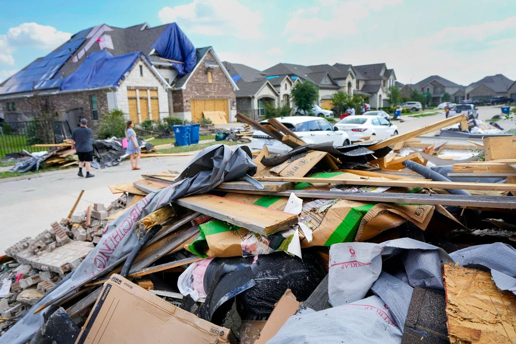 People walk through a Bridgeland neighborhood as families begin cleaning up storm damage