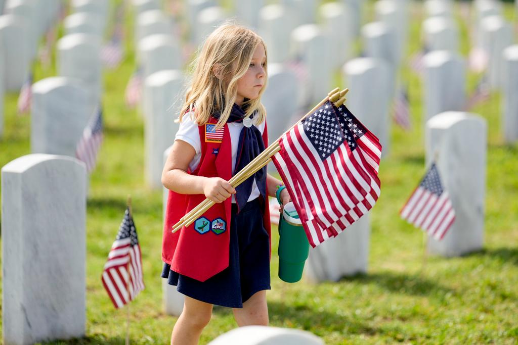 American Heritage Girl Isabel Lennon carries flags to be placed on head stones at the Middle Tennessee Veterans Cemetery in honor of Memorial Day