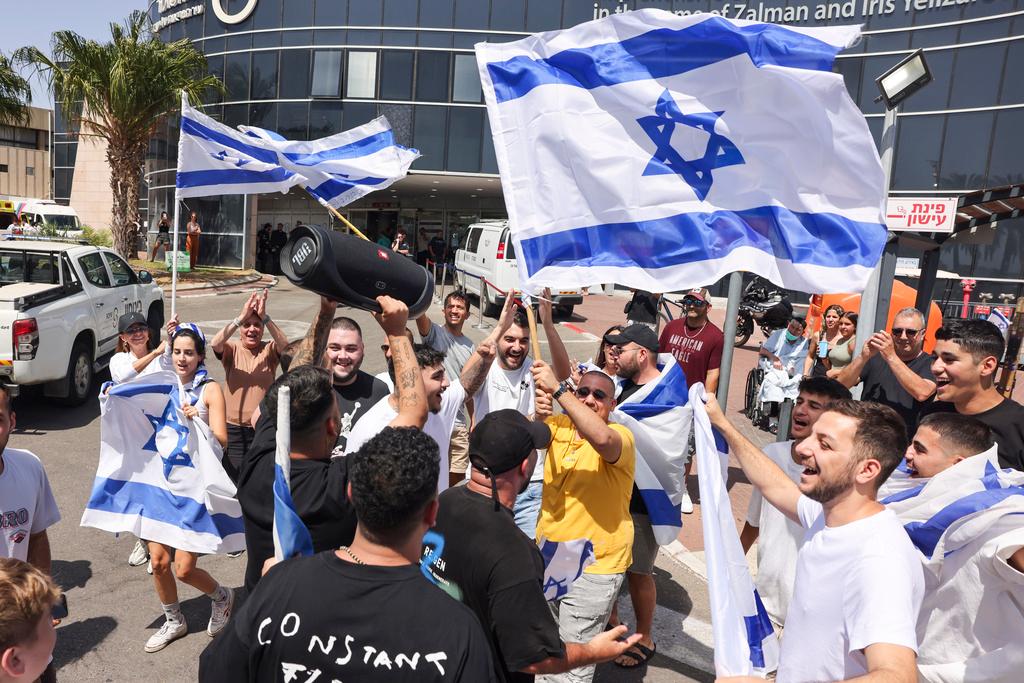 People wave Israeli flags as they celebrate after hostages who were kidnapped in a Hamas-led attack on Oct. 7. were rescued from Gaza Strip