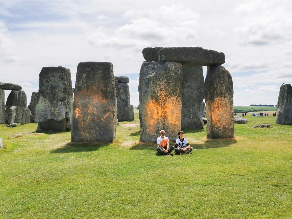 In this handout photo, Just Stop Oil protesters sit after spraying an orange substance on Stonehenge, in Salisbury, England, Wednesday June 19, 2024.