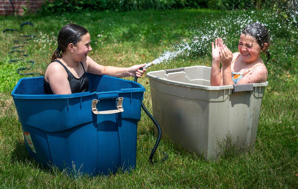 Best friends Anna Labelle, left and Frankie Russell got creative to help stay cool in Labelle's backyard in Auburn, Maine