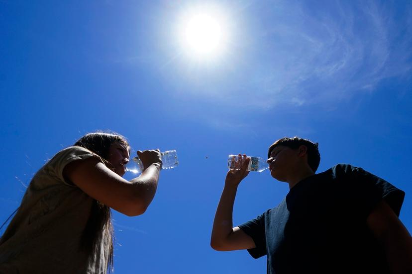 Tony Berastegui Jr., right, and his sister Giselle Berastegui chug water in Phoenix. To avoid overheating, it's key to stay hydrated. 