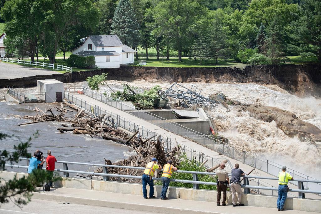 Onlookers take in the catastrophic damage to the Rapidan Dam site in Rapidan, Minn., Monday, June 24, 2024. Debris blocked the dam forcing the heavily backed up waters of the Blue Earth River to reroute along the bank nearest the Dam Store.