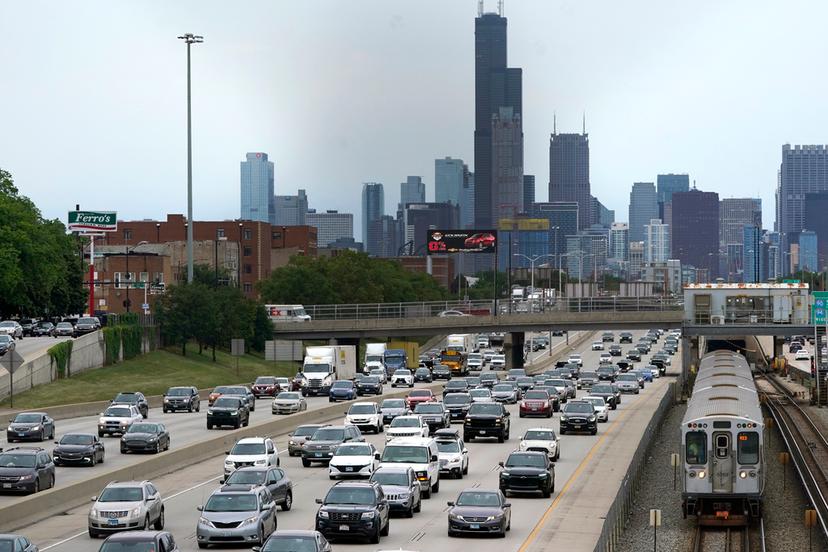 Motorists head southbound in the local and express lanes on Interstates 90-94 in slow and thickening traffic as a CTA train enters a station on the first day of the Fourth of July holiday weekend, July 1, 2022, in Chicago. 