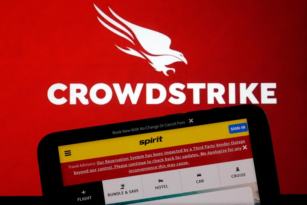 The logo for CrowdStrike and a Spirit Airlines webpage are shown on a computer screen and mobile phone screen, in New York, Friday, July 19, 2024.