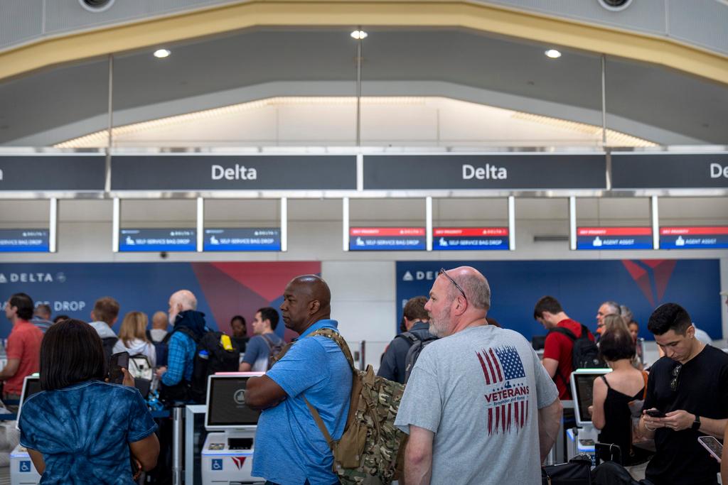 Travelers stand in line at a Delta Air Lines counter at Reagan National Airport 