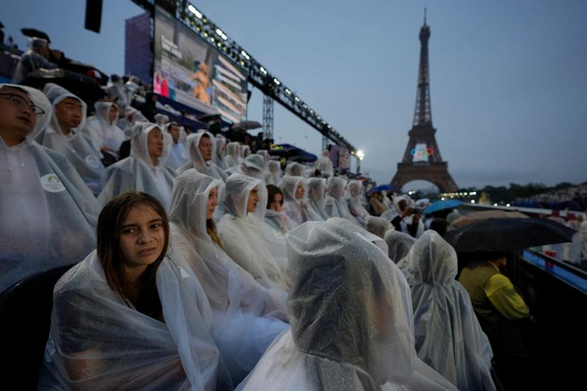 Spectators sit in the rain in Paris, France, during the opening ceremony of the 2024 Summer Olympics,