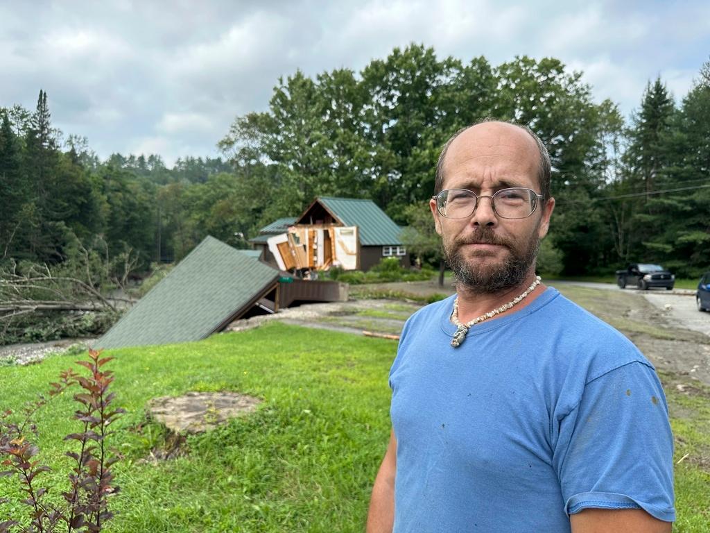 Hero Jason Pilbin stands outside flood-damaged homes in Lyndonville, Vt.