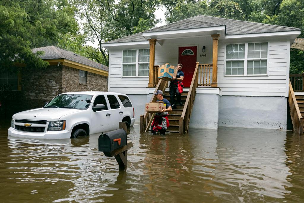 Savannah Fire Advanced Firefighters Ron Strauss, top, and Andrew Stevenson, below, carry food to residents in the Tremont Park neighborhood that where stranded in stormwater from Tropical Storm Debby, Tuesday, Aug. 6, 2024, in Savannah, Ga.