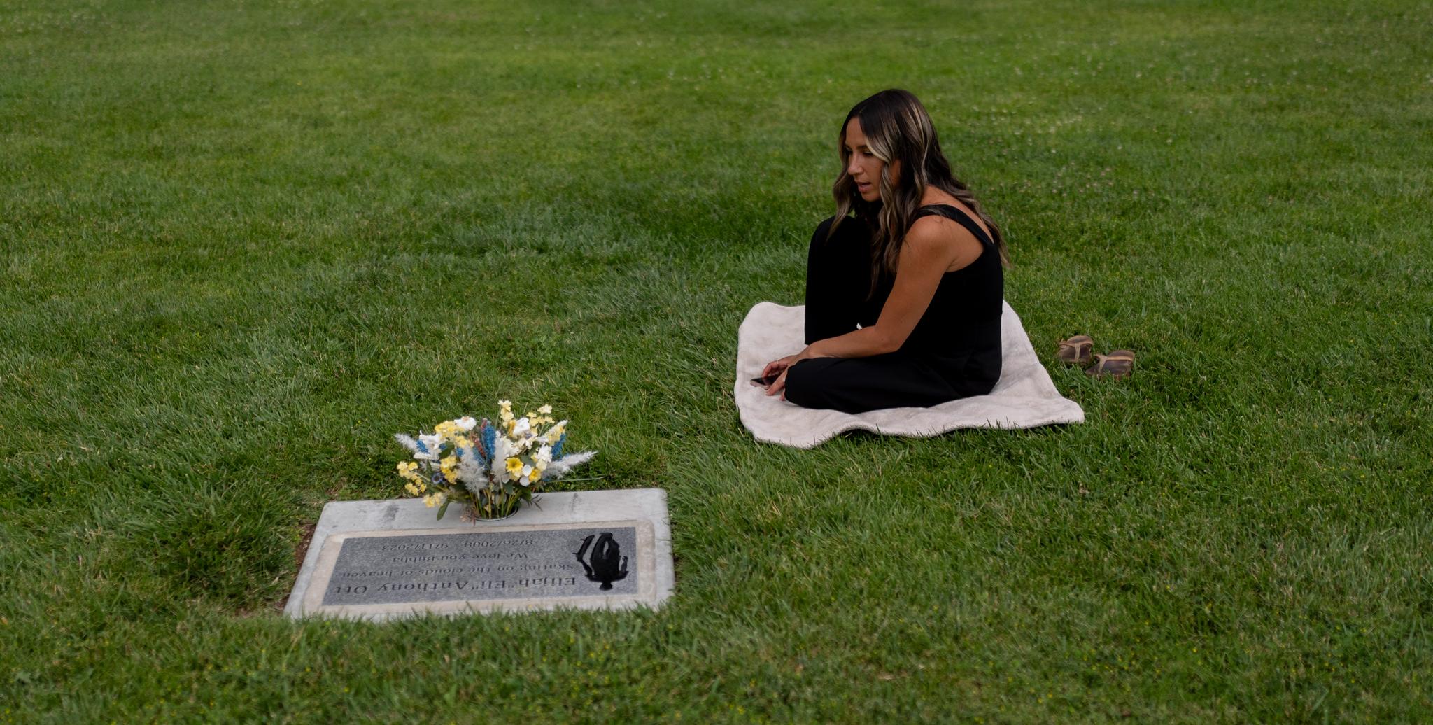 Young mom sitting at her son's gravesite