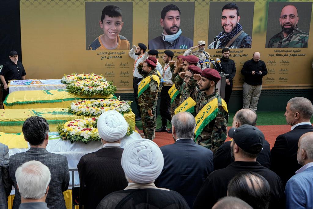 Hezbollah fighters salute as they stand next to the coffins of four victims who were killed Tuesday after their handheld pagers exploded