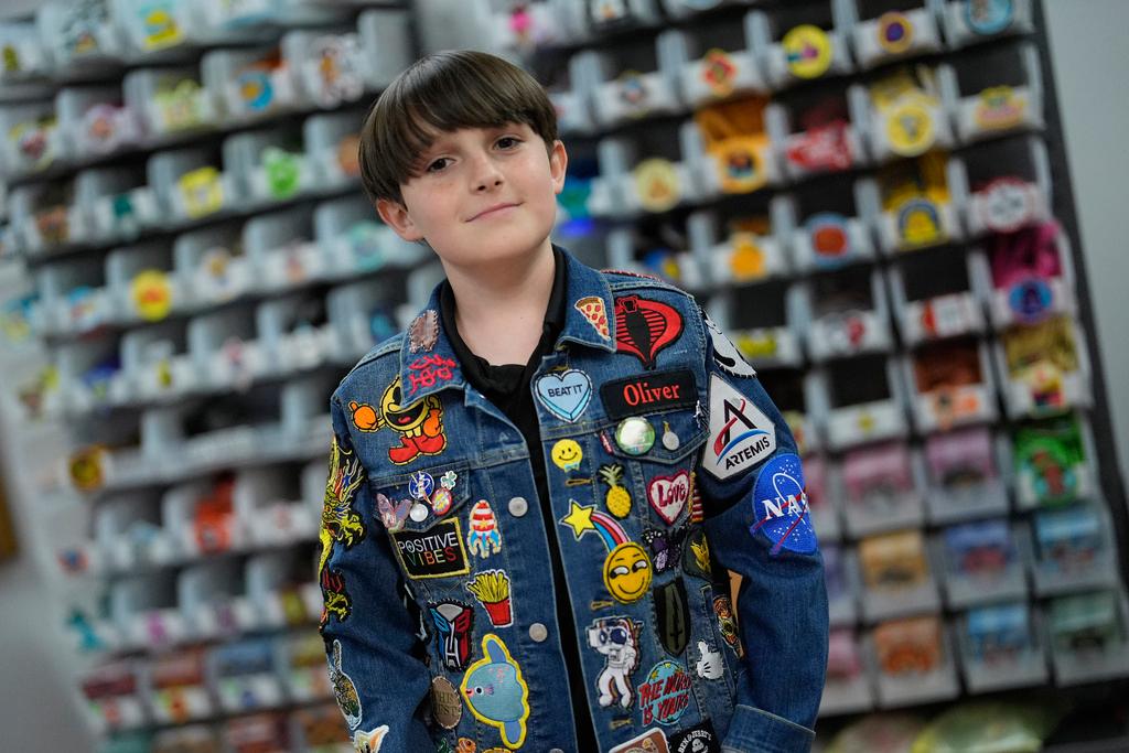 Oliver Burkhardt, 13, stands in front of trays of patches inside the offices of the Oliver Patch Project in Miami 