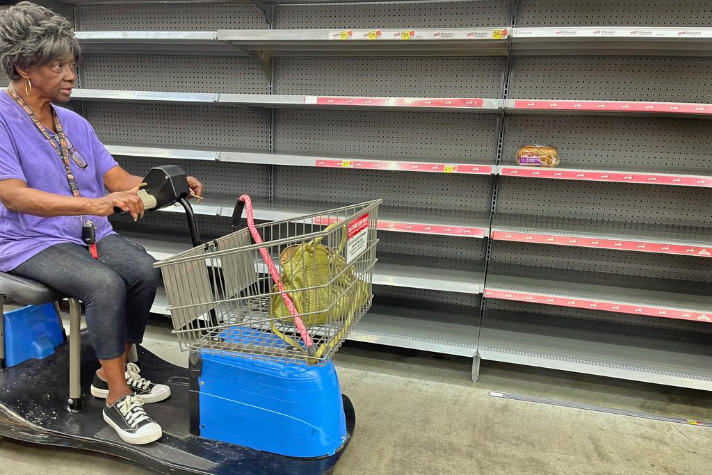 A shopper passes by empty shelves in the bread section of a Walmart in Tallahassee, Fla. 