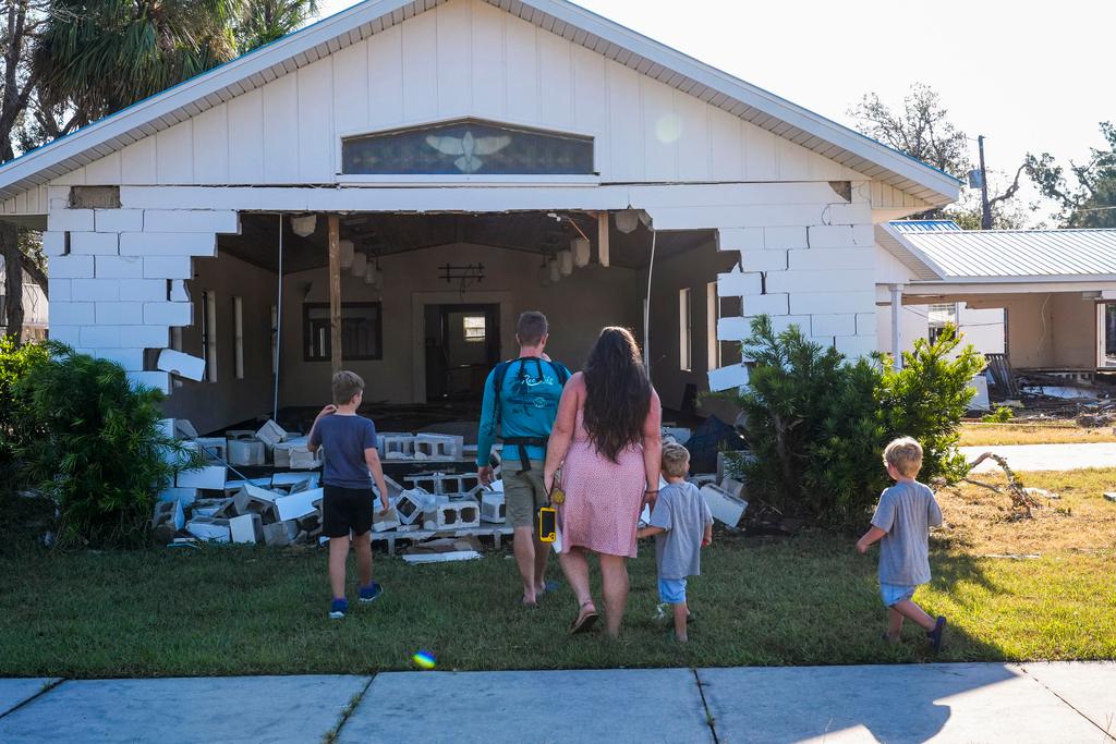 A group from St. Augustine, Fla. that arrived to help storm victims pray outside the damaged First Baptist Church in the aftermath of Hurricane Helene, in Horseshoe Beach, Fla.