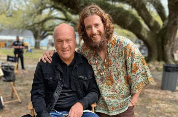 Two men smiling, one dressed in hippy clothes