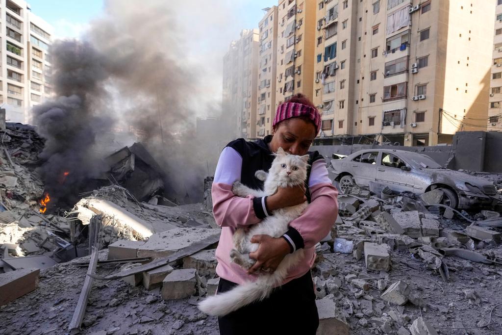 A woman holds her cat in front of a destroyed building at the site of an Israeli airstrike in Dahiyeh, Beirut, Lebanon