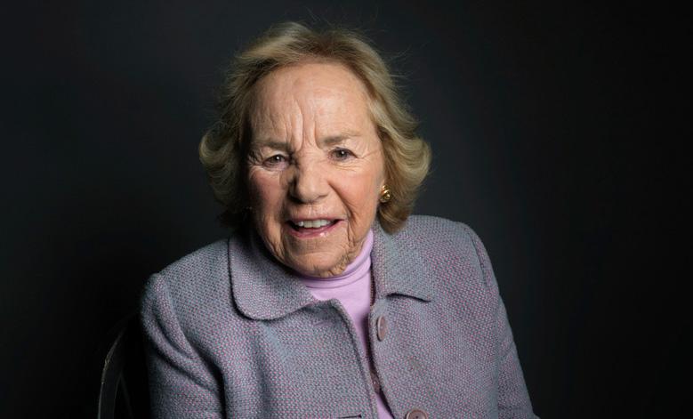 Smiling elderly woman wearing a lavendar suit