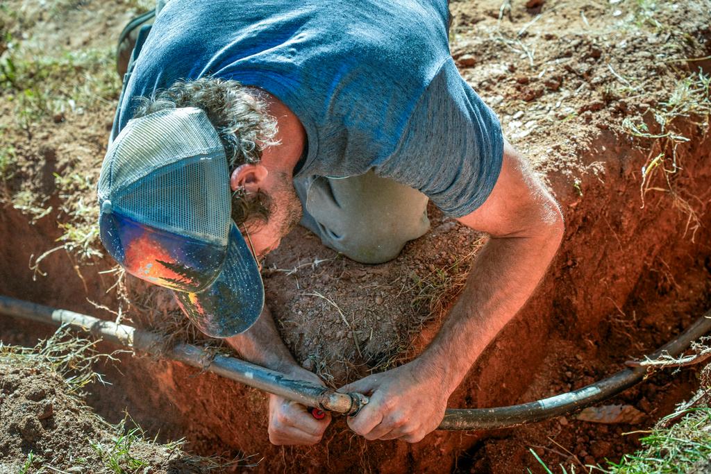 Jeffrey Martyn, a plumber and electrician works on a pipe fitting that draws water from a community well located on an urban farm that belongs to Bountiful Cities, a nonprofit organization, in Asheville, N.C. 