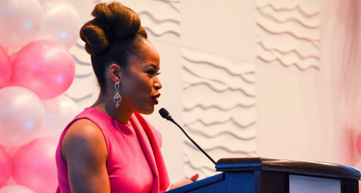 Woman in hot pink elegant dress speaking at a podium