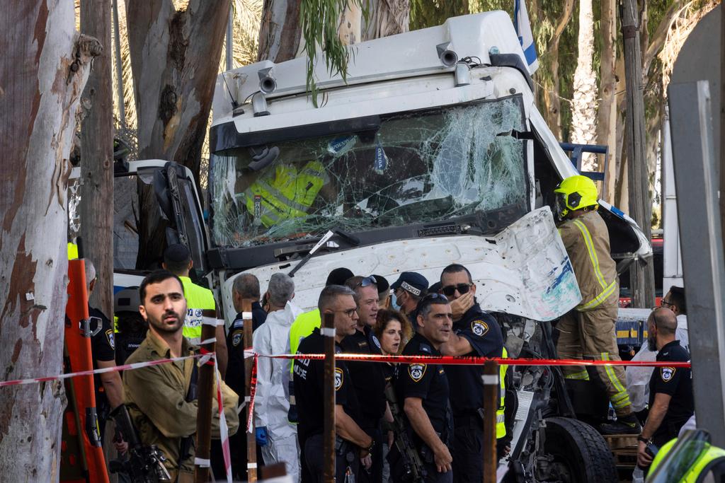 Israeli police and rescue services inspect the site where a truck driver rammed into a bus stop near an army base, wounding dozens of people