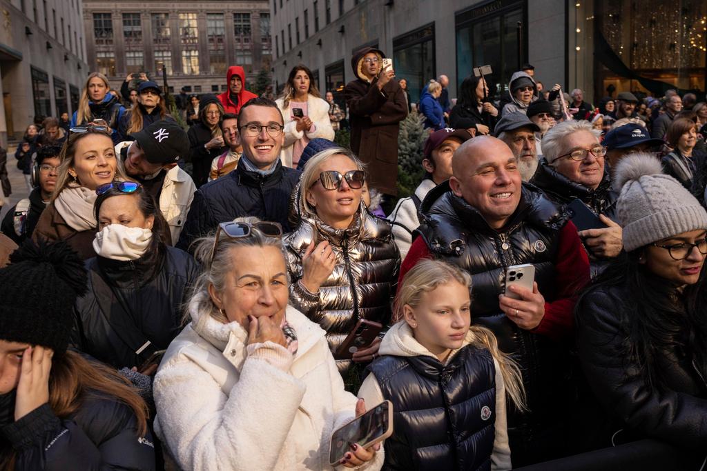 People watch the Rockefeller Center Christmas tree being lifted by a crane into place at Rockefeller Plaza