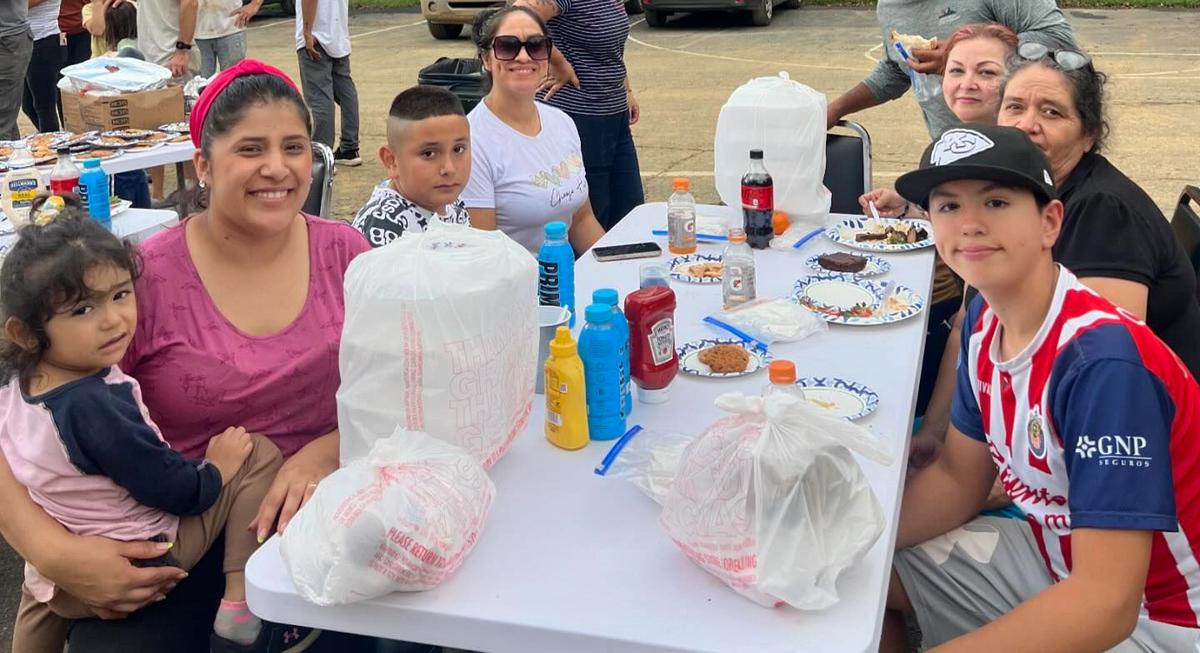 Family smiling at picnic table with food