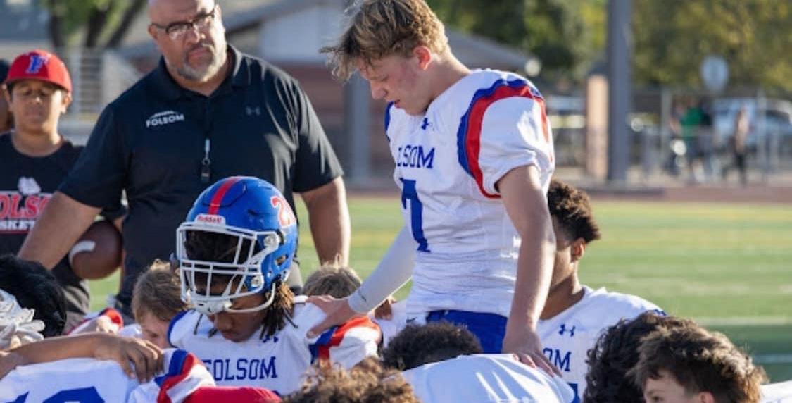 One player standing and praying for other kneeling players