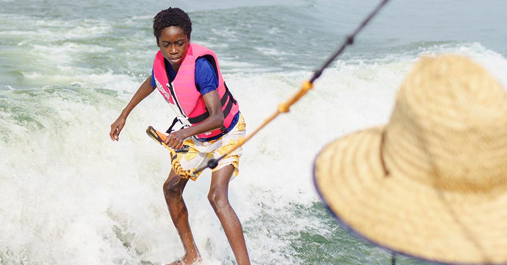 Young boy in life jacket on a wakeboard in the water