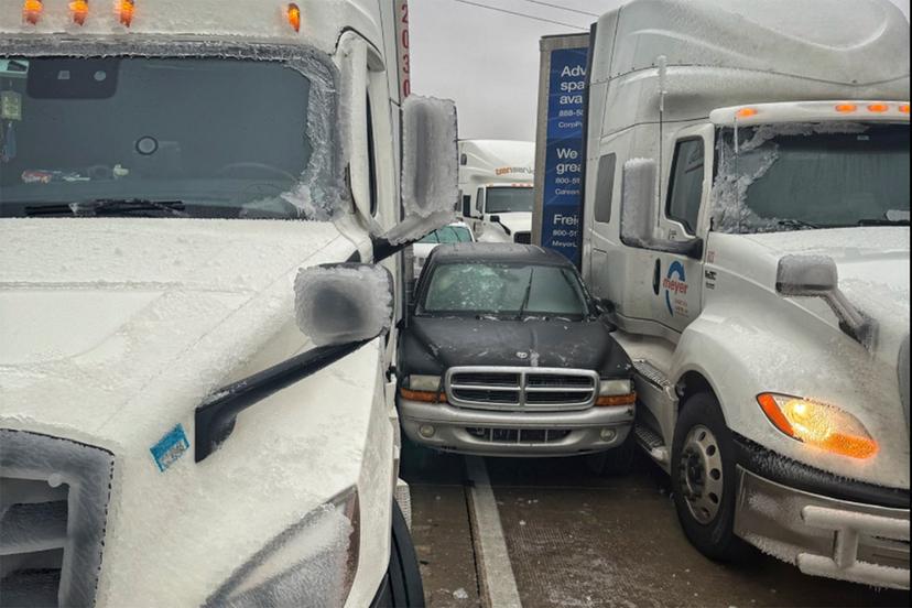 a car is wedged between two trucks during icy weather in Salina, Kansas