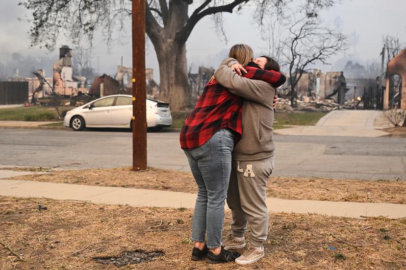 Lisa Diaz hugs a neighbor outside of their homes as the Eaton Fire sweeps through the area