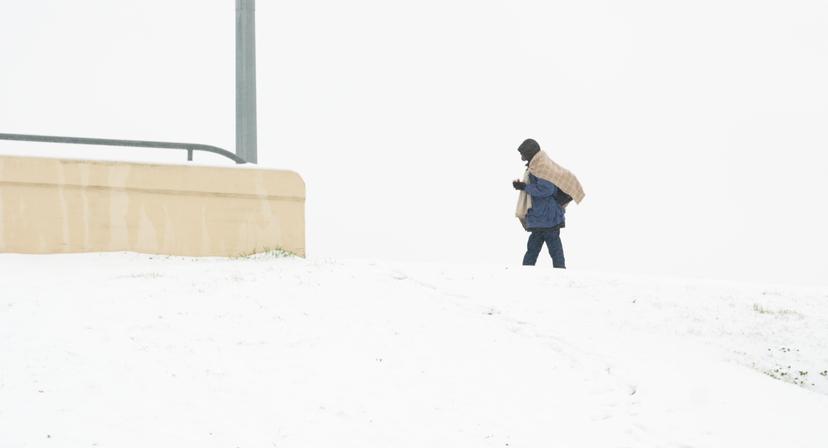 Man walks over snow-covered overpass