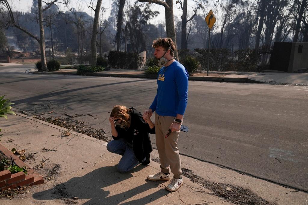 Kathleen Orlinksy prays while holding hands with her son David after finding out their home was spared in the aftermath of the Palisades Fire 