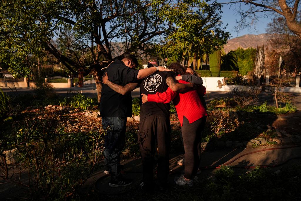 The Johnson family, whose home is one of the few that survived the Eaton Fire in their neighborhood in Altadena, Calif., prays with pastors outside their home