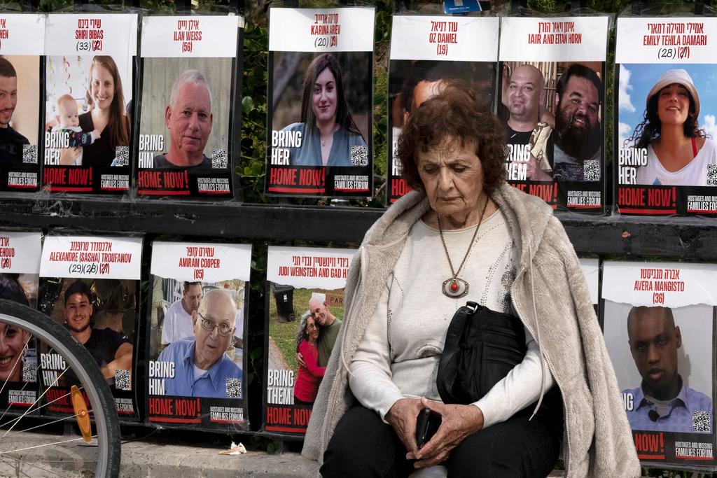 A woman pauses near posters of hostages held by Hamas in the Gaza Strip, in Tel Aviv, Israel