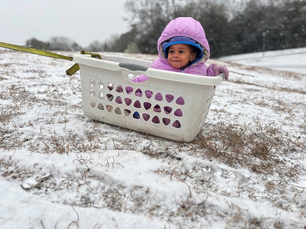 Aria Johnson, 1, enjoys snow in an improvised sled in Montgomery, Ala.