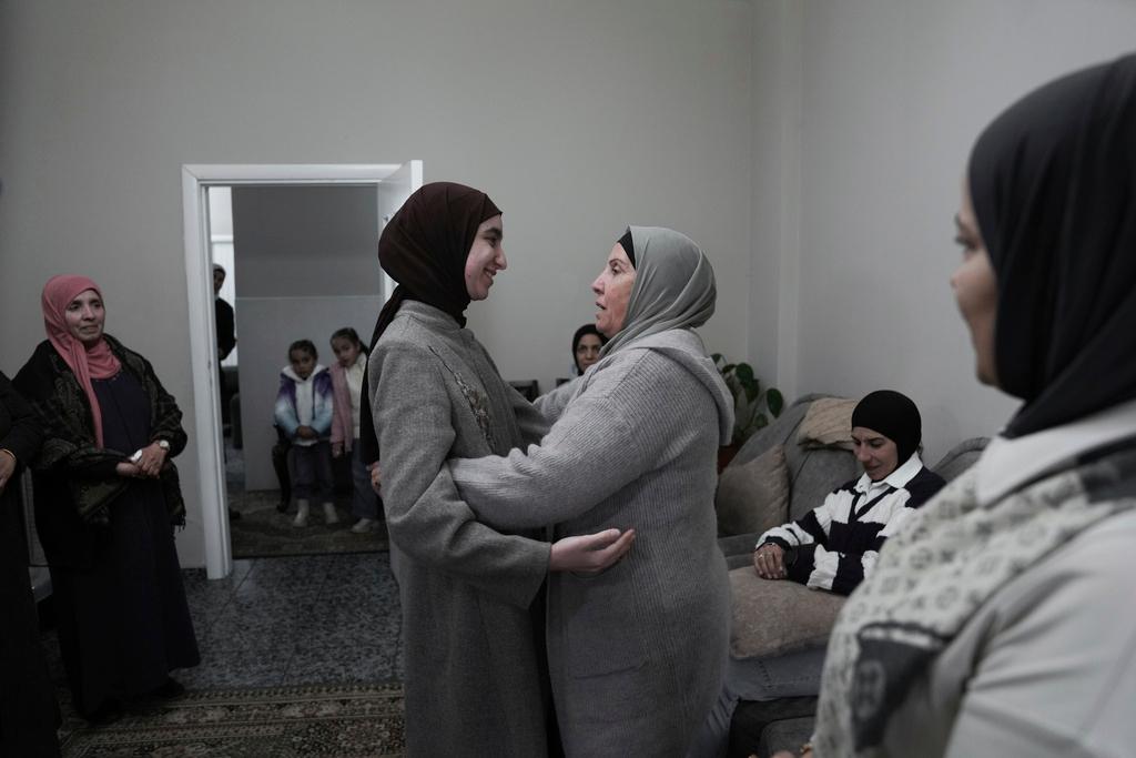 Amal Shujaeiah, a former Palestinian prisoner who was released from an Israeli prison as part of a ceasefire deal between Israel and Hamas, embraces relatives at her home in Dayr Jarir, West Bank, Monday, Jan. 20, 2025. 