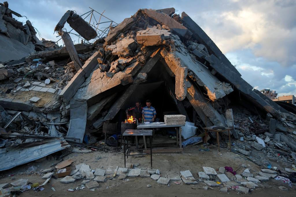 A man sells bread under the destruction of his bakery destroyed by the Israeli air and ground offensive in Jabaliya, Gaza Strip