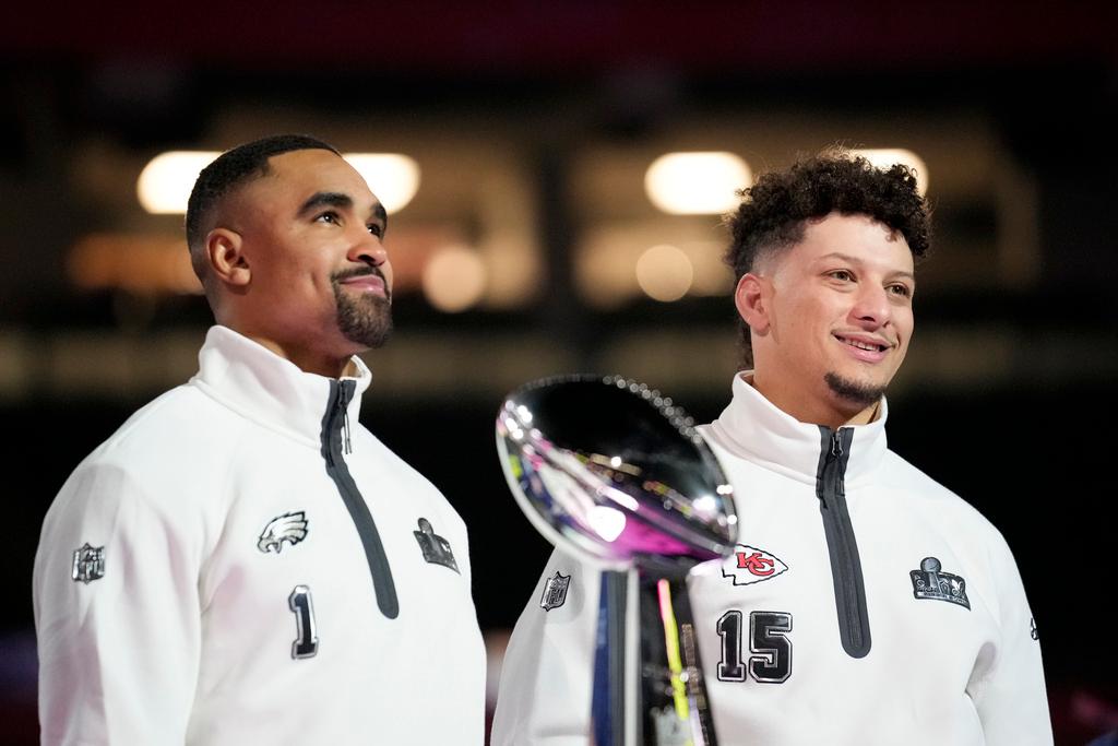 Philadelphia Eagles quarterback Jalen Hurts (1) and Kansas City Chiefs quarterback Patrick Mahomes (15) pose with the trophy during Super Bowl 59 Opening Night in New Orleans