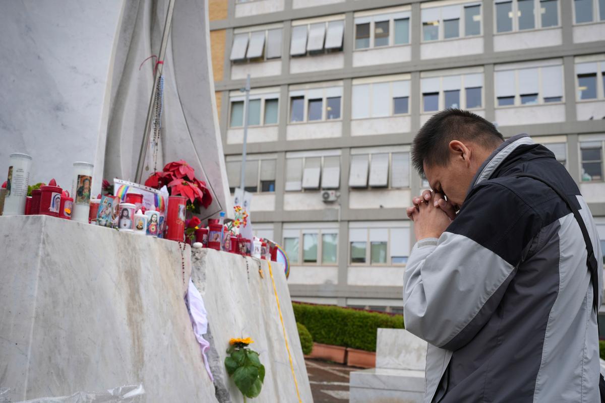 Man praying in front of altar to Pope Francis.