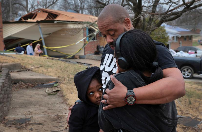 Marcus Cole embraces his daughters while standing in front of his destroyed home after a severe storm in Bridgeton, Mo.