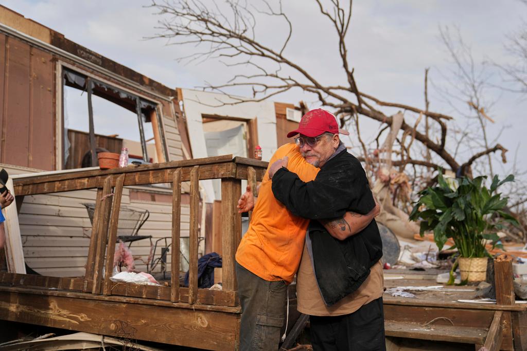 Tim Scott, right, gets a hug from friend Jorden Harris outside Scott's destroyed home 