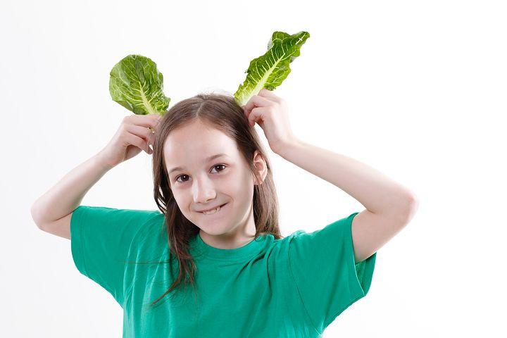 Girl carrying two green leafs on head and posing as Rabbit