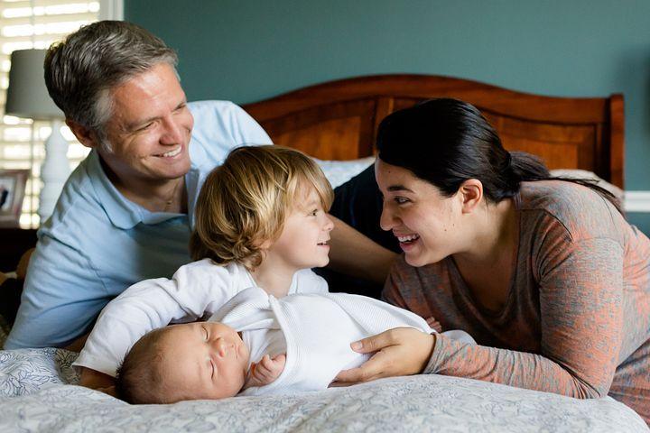 Family picture of mom,dad, toddler and infant smiling