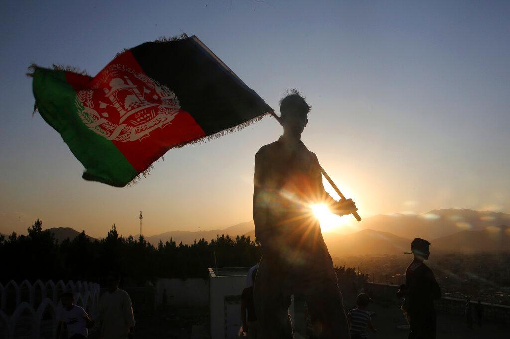 In this Aug. 19, 2019, file photo, a man waves an Afghan flag during Independence Day celebrations in Kabul, Afghanistan. An Afghan official Sunday, Feb. 9, 2020, said multiple U.S. military deaths have been reported in Afghanistan's Nangarhar province after an insider attack by a man wearing an Afghan army uniform.