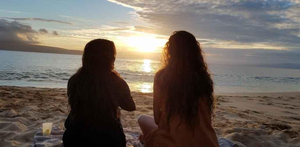 Two women sitting on beach 