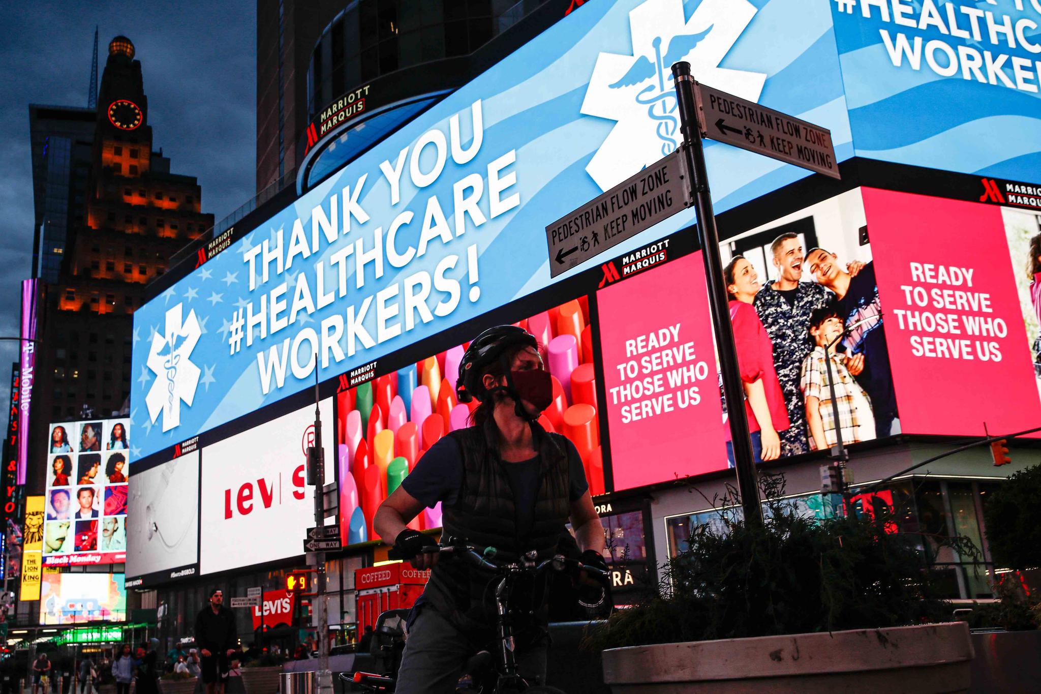 A screen displaying a messages thanking healthcare workers due to COVID-19 concerns is displayed in a sparsely populated Times Square