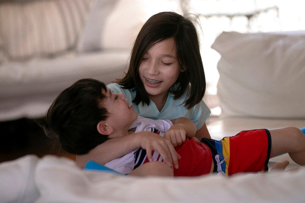 Juliet Daly, 12, plays with her brother Dominic, 5, in their family home in Covington, La., 