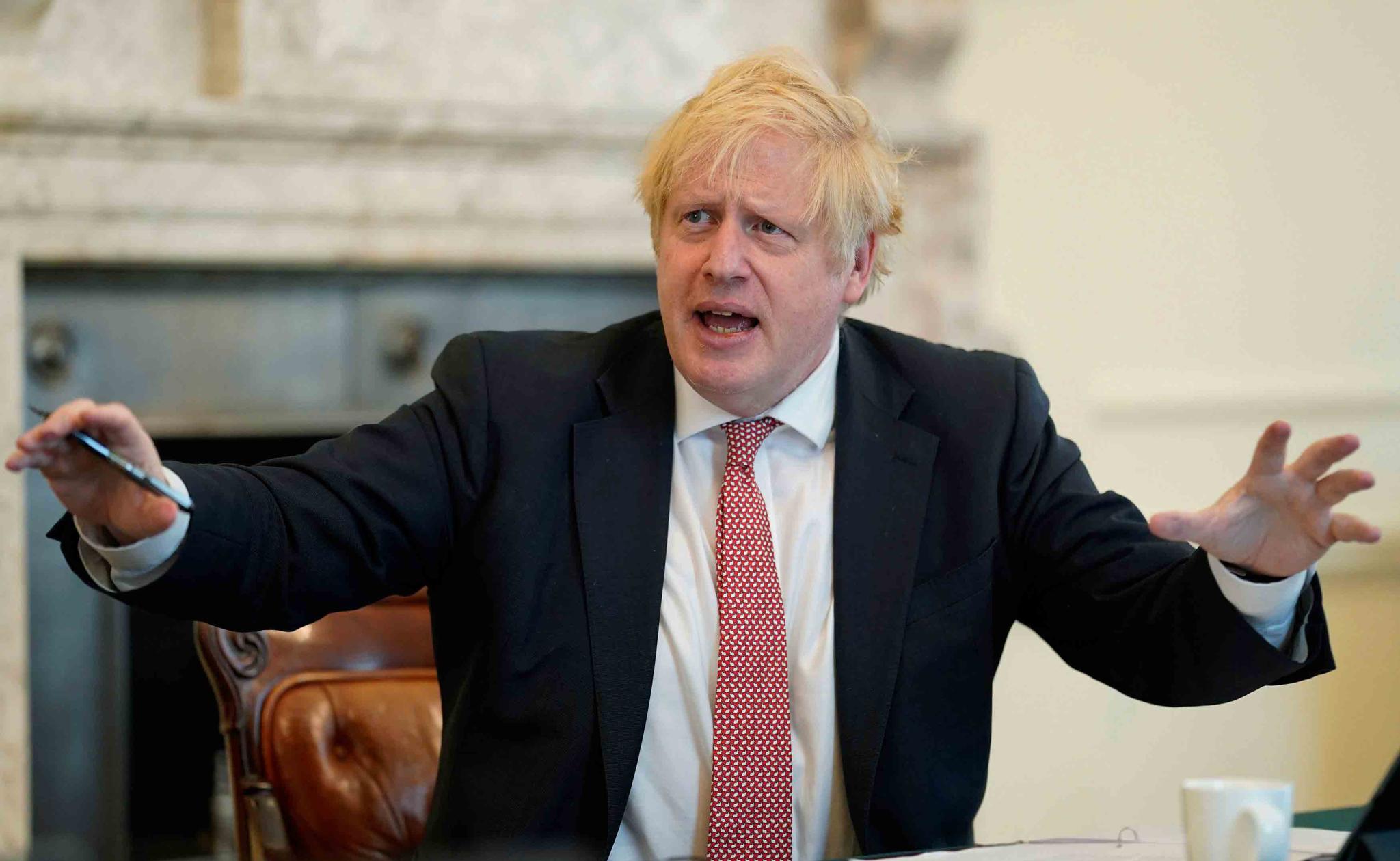 In this photo provided by 10 Downing Street, Britain's Prime Minister Boris Johnson chairs his first digital Cabinet meeting inside the Cabinet Room of No 10