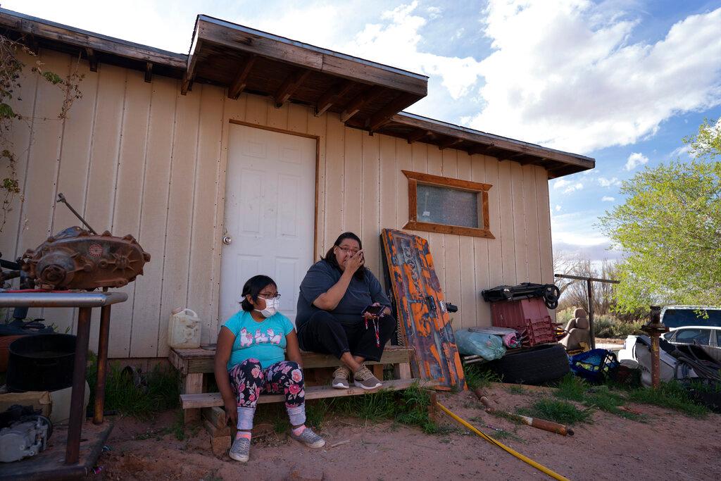 Angelina Dinehdeal wipes tears from her eyes as she sits with her 8-year-old daughter, Annabelle, on the family's compound in Tuba City, Ariz.