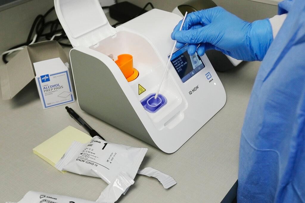 Lab technician dips a sample into the Abbott Laboratories ID Now testing machine at the Detroit Health Center in Detroit. Federal health officials are warning about potential accuracy problems with the rapid test for COVID-19 used at thousands of hospitals, clinics and testing sites 